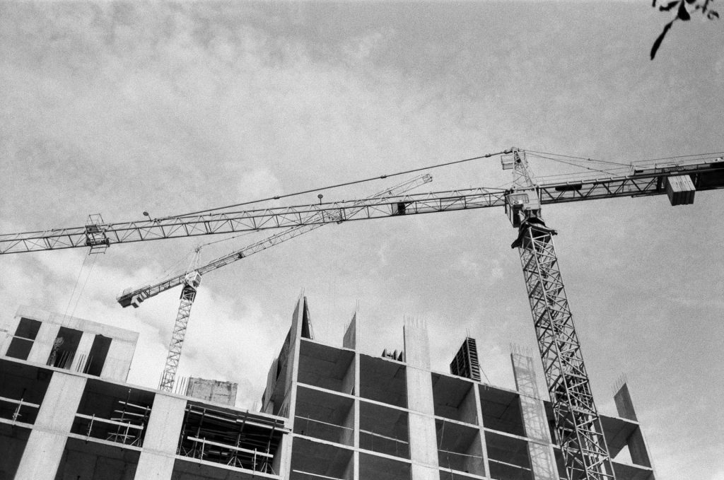 A black and white photo of a crane in front of a building