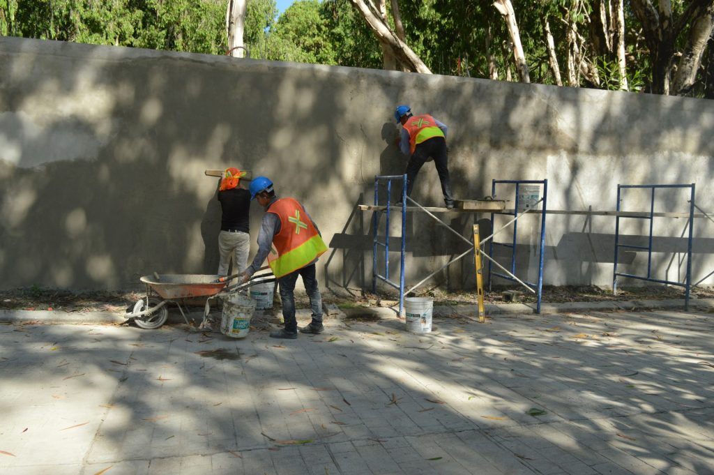 Construction workers plastering a wall on scaffolding.